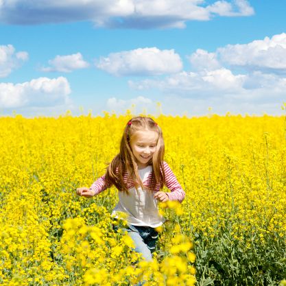 Little girl running through a meadow of yellow flowers bug free.